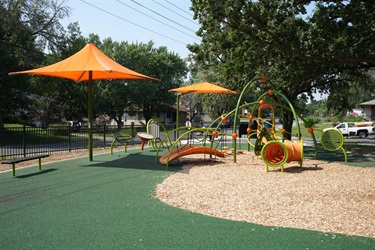 A playground set next to several canopy's with benches underneath