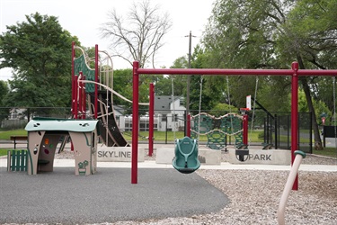 A playground set with several swings and a little shed