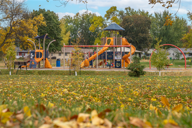 A large playground set next to a large field