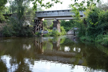 A train track runs across a bridge that extends over a lake