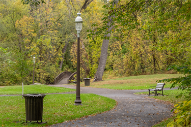 A paved trail lined with benches, lights and trash cans