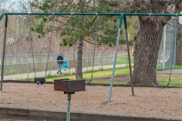 A swing set next to a trail where people walk on