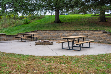 A brick fire pit surrounded by picnic tables