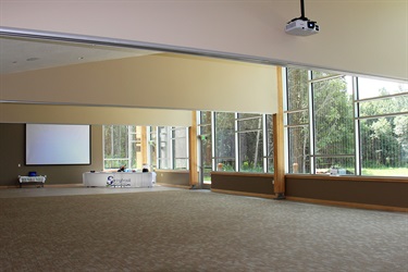 A large room with high ceiling and large windows look out into a forest