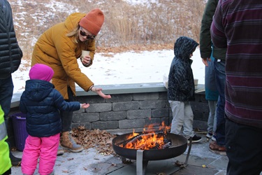 an adult and child warming up by an outdoor fire