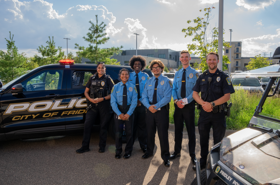 Group of Police Officers and Police Explorers posing by a squad car