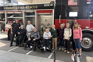 Group of Willows Bend Residents posing in front of a fire truck with firefighters