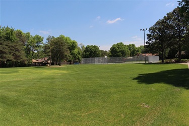A large grass field next to a tennis court