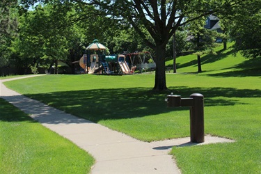 A water fountain alongside a paved trail in a park