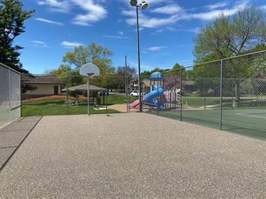 A basketball court with a playground behind it