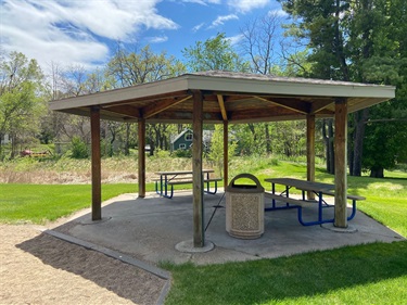 A picnic gazebo with several picnic tables underneath
